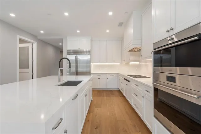 a large kitchen with stainless steel appliances granite countertop a sink and cabinets