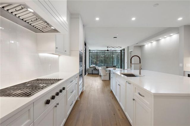 a large white kitchen with lots of counter space a sink and stainless steel appliances