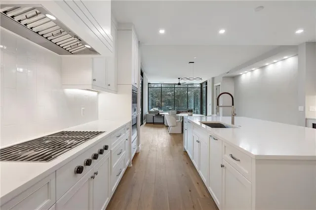 a large white kitchen with lots of counter space a sink and stainless steel appliances