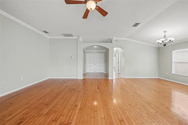 a view of empty room with wooden floor and ceiling fan