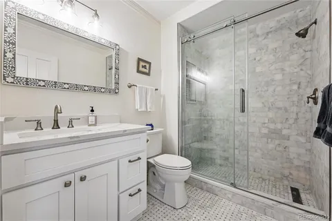 a bathroom with a shower sink vanity mirror and toilet