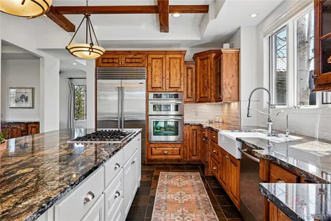 a kitchen with stainless steel appliances granite countertop a sink a stove and a wooden floors