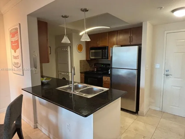 a kitchen with granite countertop a refrigerator and a sink