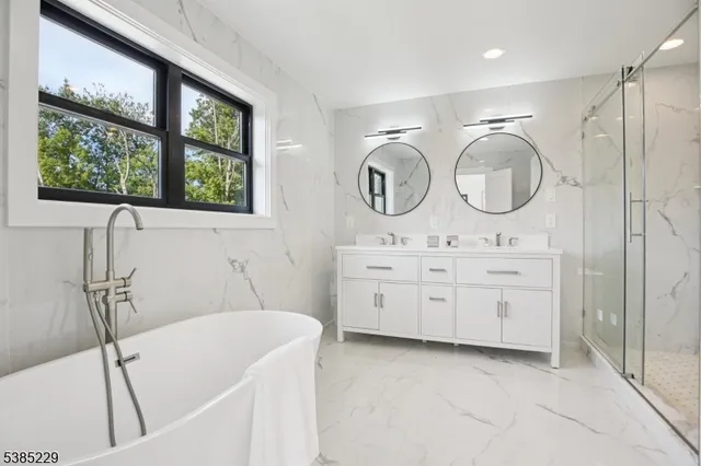 a bathroom with a double vanity sink mirror and a bathtub
