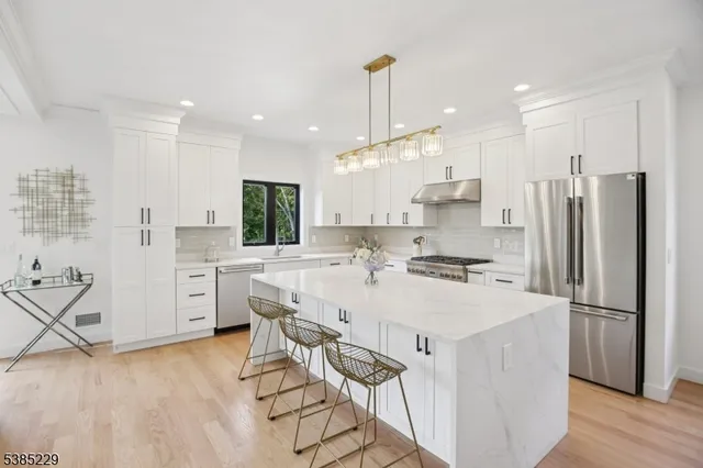 a kitchen with stainless steel appliances kitchen island a refrigerator sink and cabinets