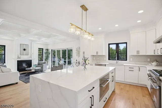 a kitchen with stainless steel appliances a sink stove and white cabinets with wooden floor
