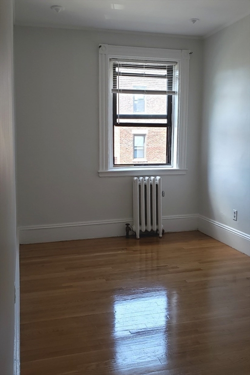 924 Beacon Street, Unit 6 Boston, MA 02215 - Photo 12 of 28 a view of an empty room with wooden floor and a window