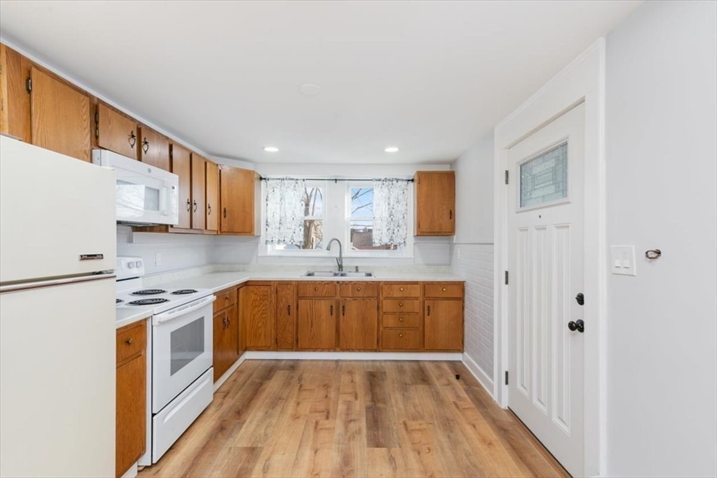 129 Friend Street, Unit 2 Amesbury, MA 01913 - Photo 4 of 27 a kitchen with stainless steel appliances granite countertop a refrigerator a stove top oven a sink and dishwasher with wooden floor