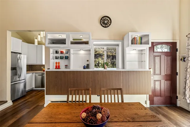 a living room with stainless steel appliances furniture a rug and a kitchen view