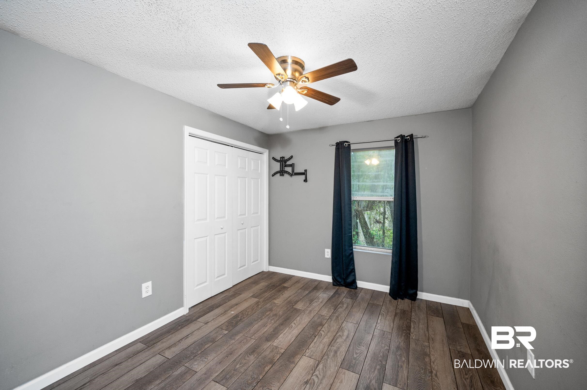 906 North Cedar Street Foley, AL 36535 - Photo 16 of 24 Unfurnished bedroom featuring a textured ceiling, dark hardwood / wood-style flooring, ceiling fan, and a closet
