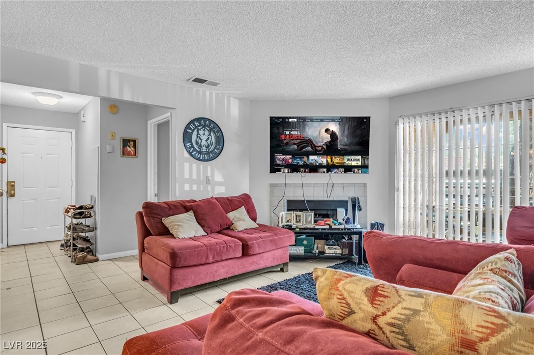 2200 South Fort Apache Road, Unit 1007 Las Vegas, NV 89117 - Photo 5 of 30 Living area with light tile patterned floors, a textured ceiling, a tile fireplace, and visible vents