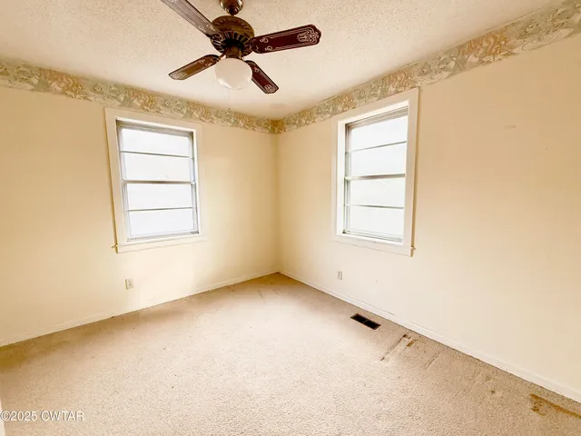 an empty room with windows and fan