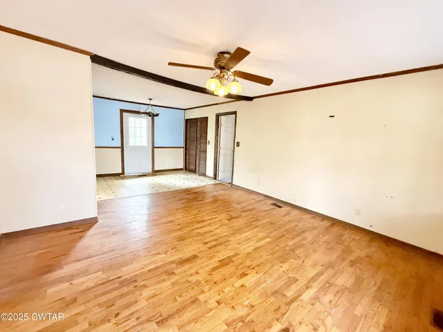 a view of a big room with wooden floor and windows