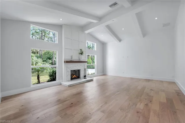an empty room with windows and fireplace