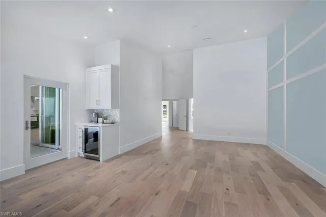 a view of empty room with wooden floor and kitchen