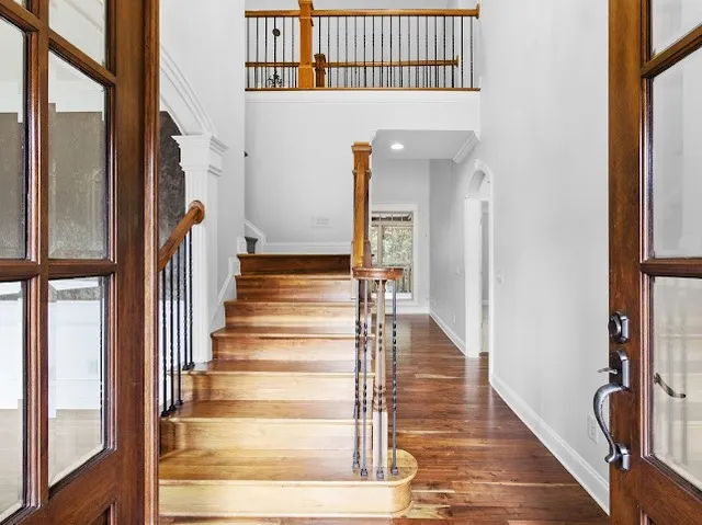 an empty room with chandelier fan and windows