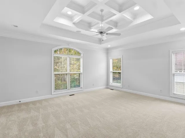 an empty room with ceiling fan and windows