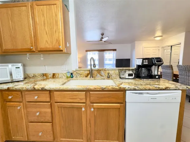 a kitchen with stainless steel appliances granite countertop a refrigerator a stove a sink dishwasher and white cabinets with wooden floor