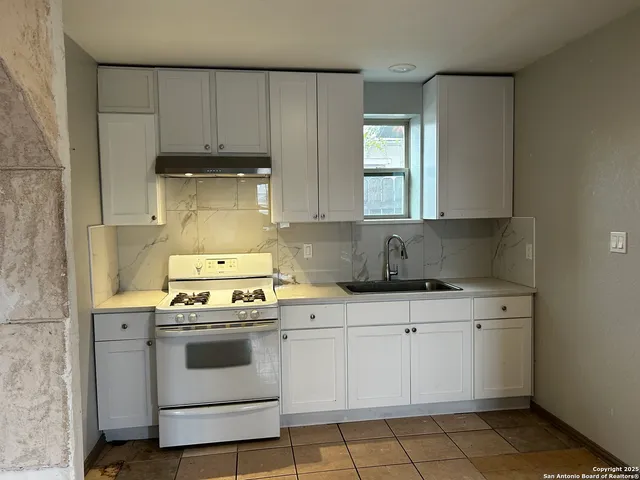 a kitchen with a stove sink and cabinets