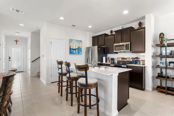 a kitchen with stainless steel appliances a refrigerator a stove a microwave oven a sink dishwasher with a dining table and chairs