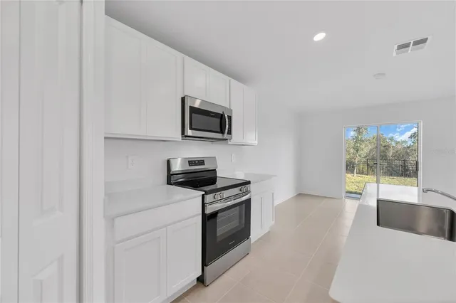 a kitchen with a stove a microwave and white cabinets
