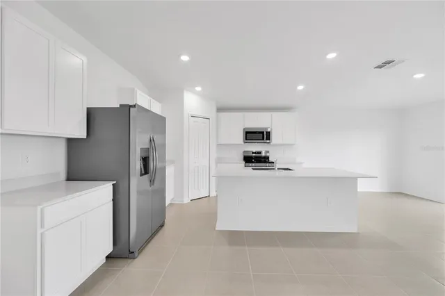 a kitchen with stainless steel appliances a refrigerator sink and white cabinets