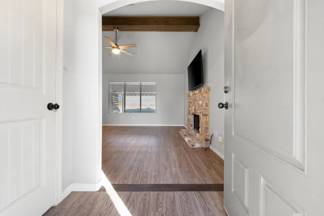 an empty room with windows fireplace and wooden floor