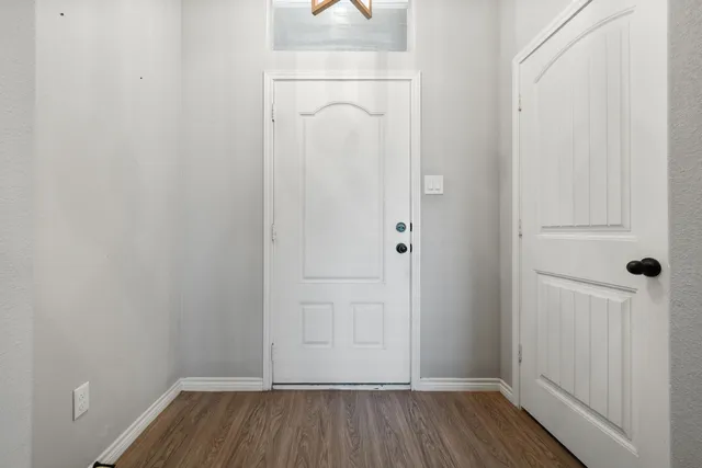 a view of empty room with wooden floor fireplace and a window