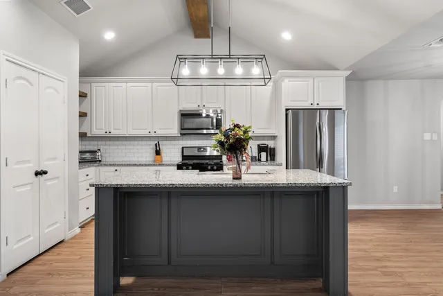 a kitchen with stainless steel appliances granite countertop a stove and a wooden floors