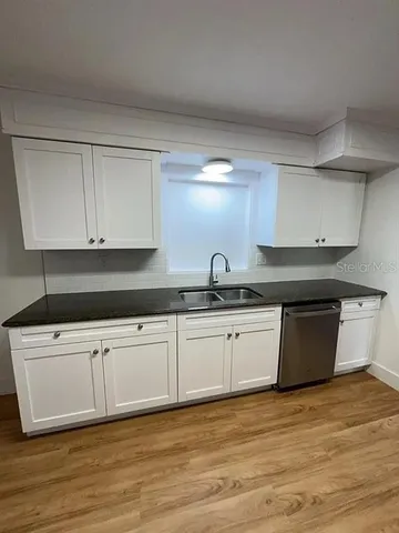 a kitchen with granite countertop a sink stove and cabinets