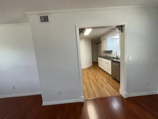 wooden floor in an empty room with a kitchen