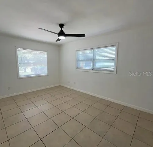 an empty room with windows and fan