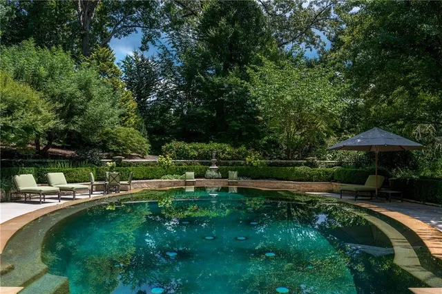 a view of a swimming pool with lawn chairs under an umbrella
