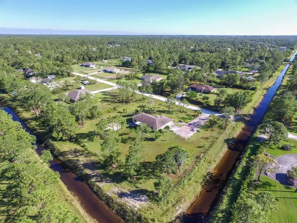 an aerial view of residential houses with outdoor space and trees