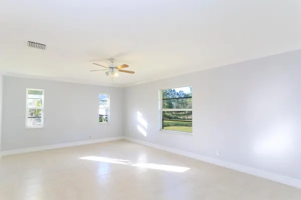 an empty room with windows and fan