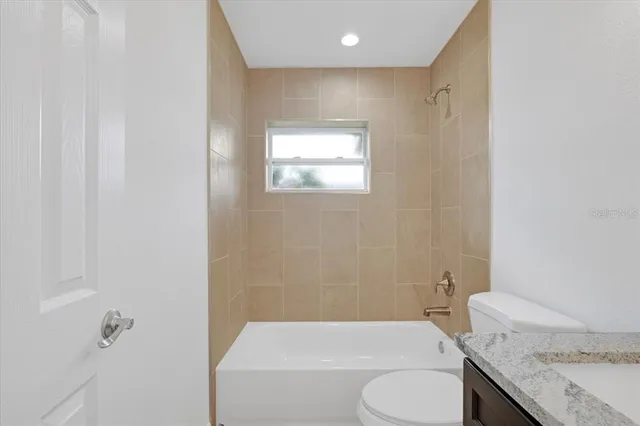 a bathroom with a granite countertop toilet sink and mirror