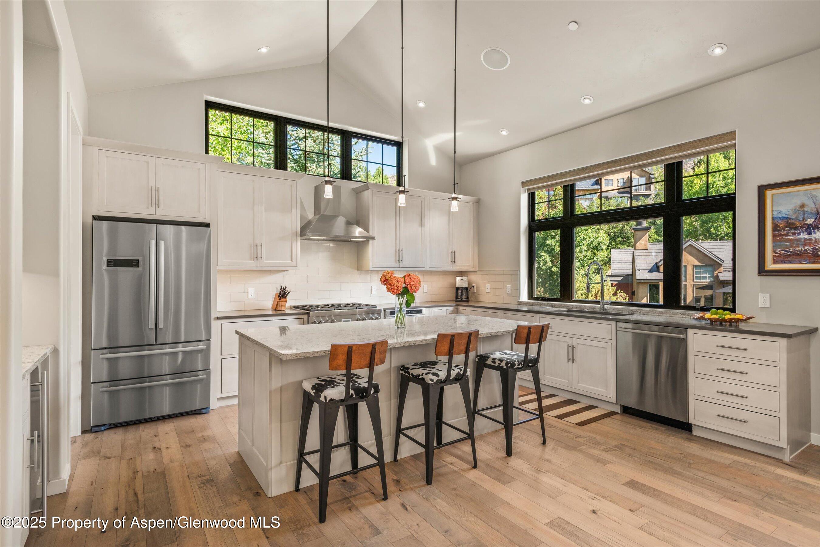 102 Wild Spring Lane Basalt, CO 81621 - Photo 25 of 51 a kitchen with stainless steel appliances granite countertop a stove a refrigerator a sink a dining table and chairs with wooden floor