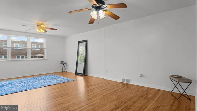 a view of an empty room with window and wooden floor