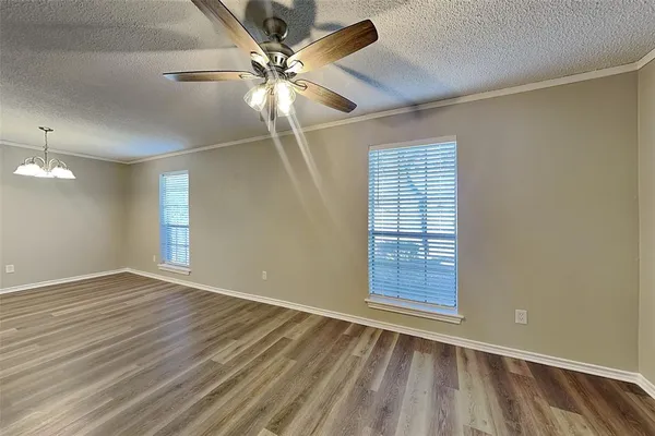 an empty room with wooden floor fan and windows