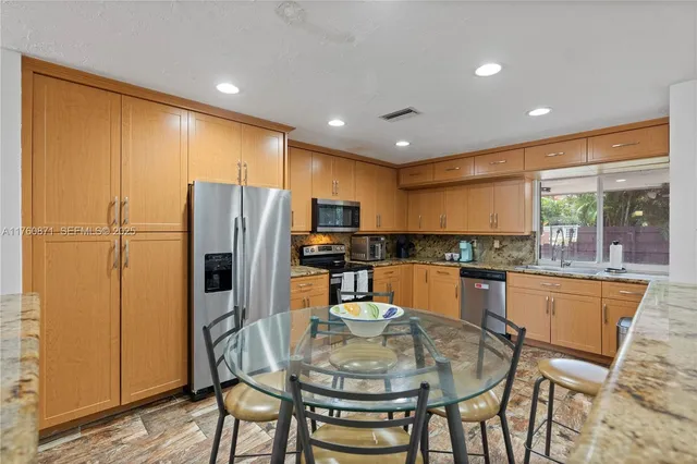 a kitchen with stainless steel appliances granite countertop a stove a refrigerator a microwave oven with a dining table and chairs