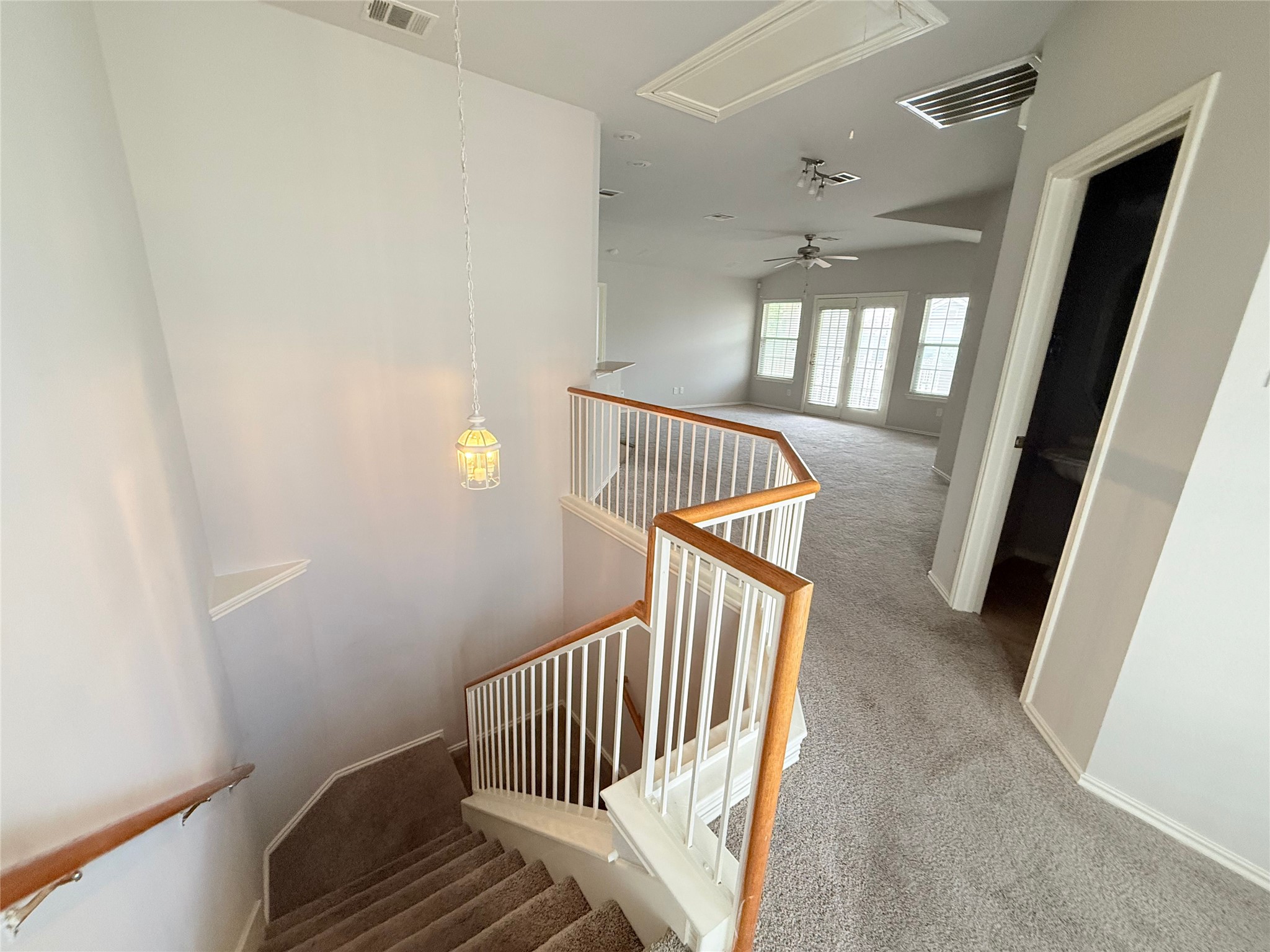 1900 Scofield Ridge Parkway, Unit 4701 Austin, TX 78727 - Photo 20 of 27 A graceful staircase ascends to a well-lit living area featuring multiple windows and neutral carpeting.