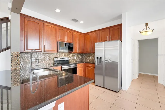 a kitchen with stainless steel appliances granite countertop a refrigerator a stove a sink and a microwave