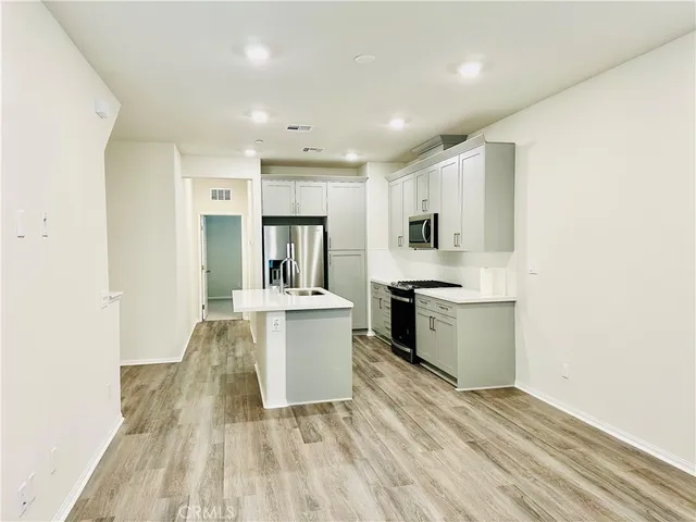 a large white kitchen with sink a microwave and cabinets