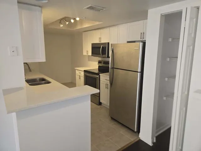 a kitchen with a refrigerator a stove top oven and cabinets