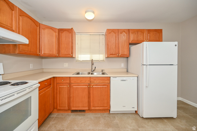 916 Vics Road, Unit 2 Sandy, UT 84094 - Photo 9 of 23 Functional kitchen featuring wood cabinetry, laminate countertops, a double basin sink with a high-arc faucet, and tiled flooring