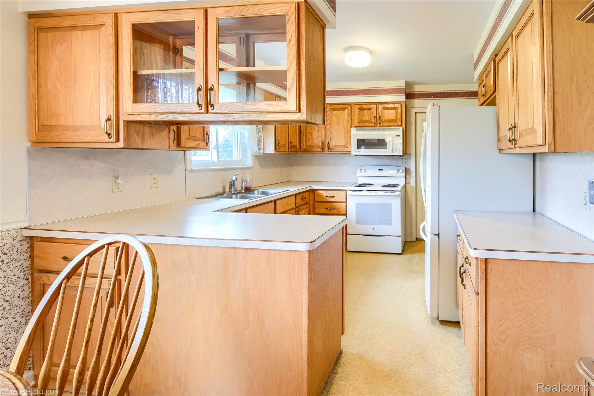 6080 Shattuck Road Saginaw, MI 48603 - Photo 14 of 35 Kitchen with white appliances, light countertops, glass insert cabinets, light floors, and a peninsula