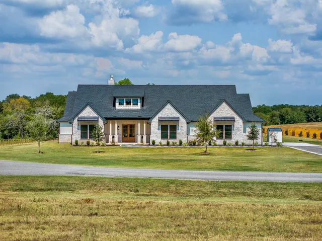 a front view of a house with a big yard and a large trees
