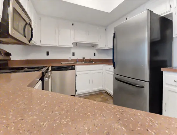 a kitchen with stainless steel appliances granite countertop a refrigerator a stove and a sink