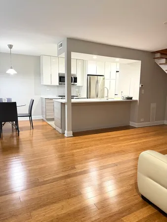 a living room with hard wood floors and kitchen view