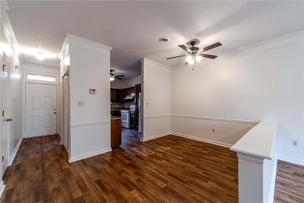 an empty room with wooden floor fan and windows